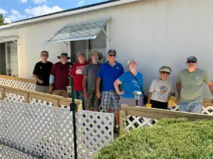 A group of people stand on a newly-built ramp in front of a client's home.